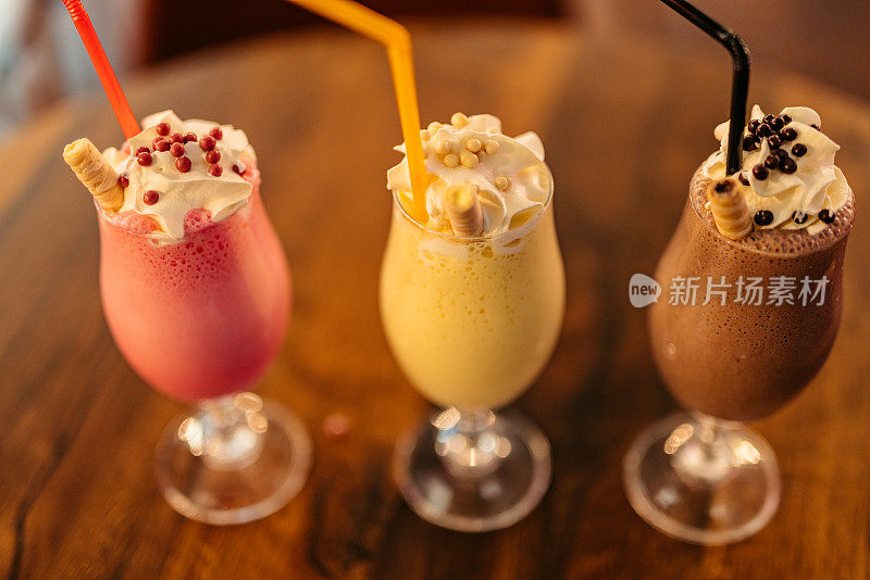 Strawberry, Vanilla And Chocolate Milkshake On A Table In A Café